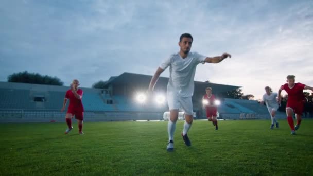 Fotbollsspelare springer och sparkar bollen följd av motståndare spelare — Stockvideo