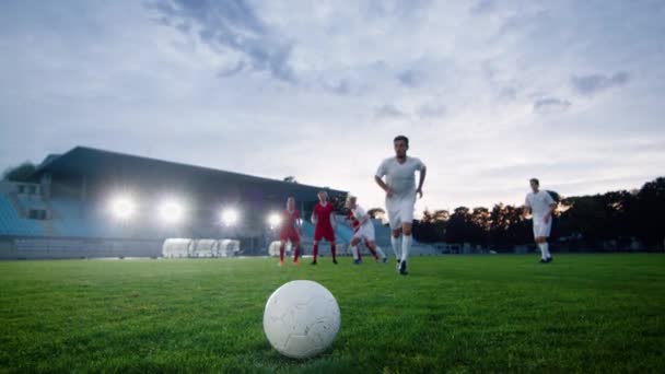 Jugador de fútbol corre y patea la pelota seguido por jugadores oponentes — Vídeos de Stock