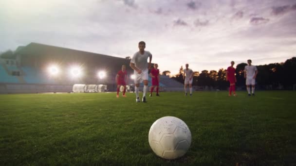 Футболист пинает мяч, в то время как оппоненты бегут за ним — стоковое видео