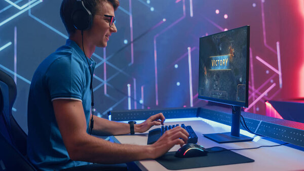 Professional eSports Gamer Wins in RPG MOBA Mock-up Video Game on His Personal Computer. He is Using Headset. Cyber Gaming Stylish Retro Neon Room