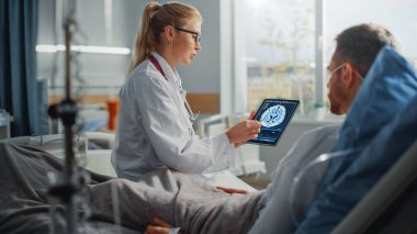 Hastane Koğuşu: Dost Canlısı Kadın Doktor Hasta Hasta Hasta ile Konuşuyor, Tablet Bilgisayar Kullanıyor, Beyin Taraması Sonuçlarını Açıklıyor. Doktor, ameliyattan sonra iyileşen bir adamla konuşuyor.