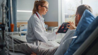 Hastane Koğuşu: Dost Canlısı Bayan Doktor Hasta Hasta Hasta Hasta ile Konuşuyor, Tablet Bilgisayar Kullanıyor, Kalp Tarama Sonuçlarını Açıklıyor. Doktor, ameliyattan sonra iyileşen bir adamla konuşuyor.
