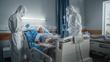 Coronavirus Hastanesi Acil Durum Bölümü: Doktorlar, örtülü sağlık görevlileri, Kıdemli Kadın Maskeler Oksijen Maskesiyle Yatakta Yatan, Iv Drip 'i Bağla, Kalp Oran Sensörü