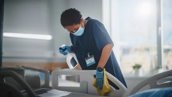 Hospital Ward: Enfermera negra profesional que usa mascarilla facial, limpia la cama, sala de limpieza después de que los pacientes de Covid-19 se recuperen. Clínica de desinfección, esterilización y desinfección después de la infección por Coronavirus — Foto de Stock