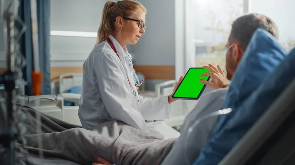 病棟:ベッドで病気の男性患者の休憩に優しい女性医師の話,緑のクロマキー画面のタブレットコンピュータを表示します。外科手術後の回復する男と医師の話 — ストック写真