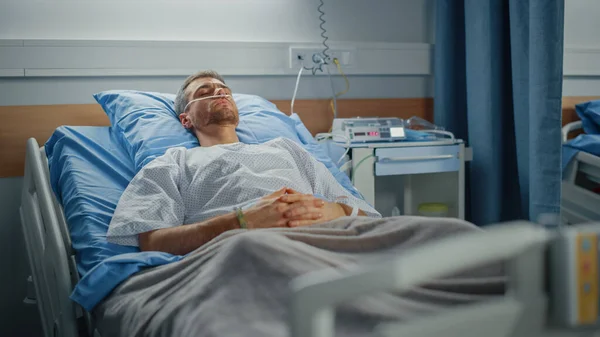 Hospital Ward: Portret van een knappe jongeman die een neuscanule draagt, slapend in bed, volledig herstellend na de ziekte. Man patiënt dromen over zijn lange en gelukkige toekomst leven — Stockfoto