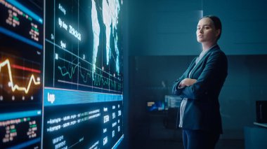 Genç Kadın Bilgisayar Bilimi Mühendisi Büyük Ekran 'a bakıyor ve Veri Göstergeleriyle Küresel Haritayı gösteriyor. Sunucularla Telekomünikasyon Teknolojisi Sistem Kontrolü ve İzleme Odası.