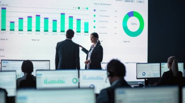 İki Tüccar, Modern İzleme Ofisinde Büyük Dijital Ekranla Analitik Kaynak Yapıyor. Komisyoncular ve Finans Uzmanlarıyla İzleme Odası Bilgisayarların Önünde Oturuyor. Meslektaşlar Konuşur.