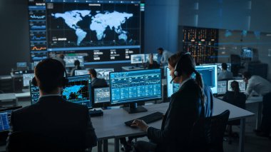 Büyük Dijital Ekrandaki Küresel Haritadan Canlı Ananliz Kaynağı ile Bir Bilgisayar Üzerinde Kadın Uzman Çalışıyor. Çalışanlar, Finansal Borsa Ticareti Bilgileri ve Büyük Verilerle Ekranların Önünde Oturuyorlar.