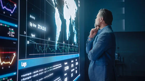 Senior Computer Science Engineer Blick auf die Großbildleinwand, die eine Weltkarte mit Datenpunkten zeigt. Telekommunikationstechnologie Unternehmen System Control and Monitoring Room mit Servern. — Stockfoto