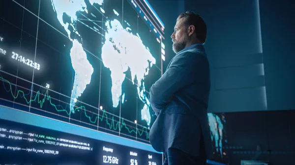 Kıdemli Bilgisayar Bilimi Mühendisi Büyük Ekran Görüntüsü 'ne bakıyor. Küresel Haritayı Veri Noktalarıyla Gösteriyor. Sunucularla Telekomünikasyon Teknolojisi Sistem Kontrolü ve İzleme Odası.