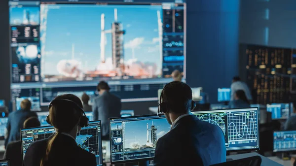 Gruppe af mennesker i Mission Control Center Witness Succesfuld Space Rocket Launch. Flight Control Medarbejdere sidder i front computer viser og overvåge bemandet mission. - Stock-foto