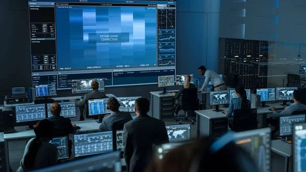 Grupo de Pessoas no Centro de Controle de Missão Tentando Estabelecer Conexão de Vídeo em uma Tela Grande com um Astronauta a bordo de uma Estação Espacial. Cientistas de Controle de Voo sentam-se em monitores de computador frontal. — Fotografia de Stock