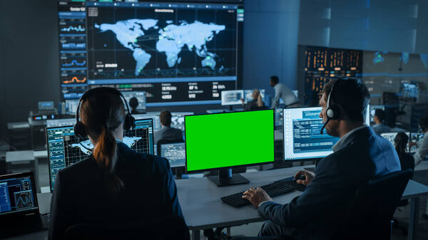 На большом цифровом экране появляется зеленый экран, который используется в Центре управления наблюдением с отслеживанием глобальных карт. Сотрудники наблюдательной комнаты анализируют большие данные.