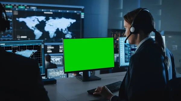 女性テクニカルクライアントサポートスペシャリストが使用するコンピュータディスプレイ上の緑色の画面水平モックアップ。ビッグデータを活用したディスプレイの制御・監視室で働くエンジニアチーム. — ストック写真