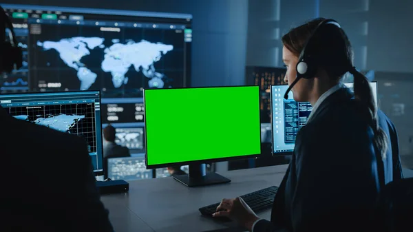 Grøn skærm Vandret Mock Up på en Computer Display Bruges af en kvindelig teknisk klient support specialist. Team of Engineers arbejder i kontrol- og overvågningsrum med skærme med Big Data. - Stock-foto