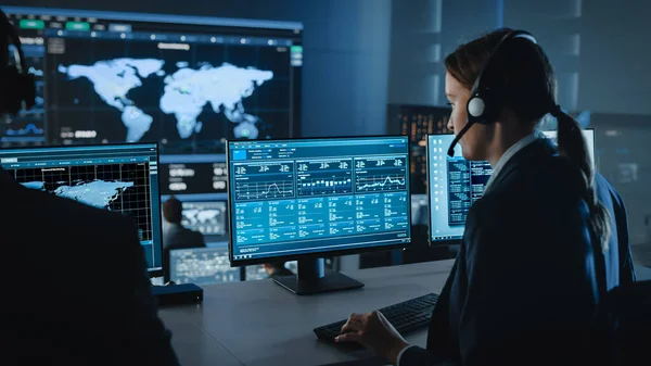 Vrouwelijke Specialist werkt op een computer met Live Ananlysis Feed van een Global Map op een groot digitaal scherm. Medewerkers zitten voor Displays met Financial Stock Trading Info en Big Data. — Stockfoto