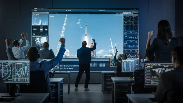 Grupo de personas en el Centro de Control de Misión Lanzamiento de cohetes espaciales para testigos. Director de vuelo está caminando nerviosamente delante de la pantalla. —  Fotos de Stock