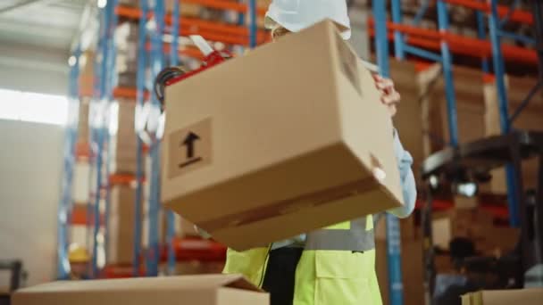 大きな倉庫で女性労働者はシールテープディスペンサー付き段ボール箱を密封します — ストック動画