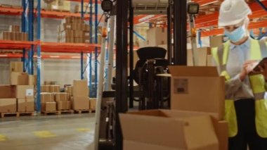 Yüz maskesi takan Depo Kadın İşçisi Dijital Tablet Bilgisayarı Kullanıyor