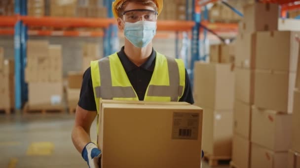 フェイスマスクを身に着けている大きな倉庫労働者は段ボール箱を運ぶ — ストック動画
