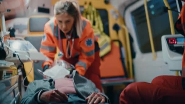 Парамедики, оказывающие медицинскую помощь пациенту в скорой помощи — стоковое видео