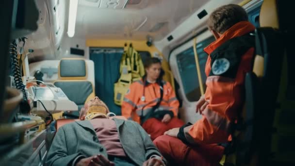 Paramédicos cavalgando em ambulância com paciente ferido — Vídeo de Stock