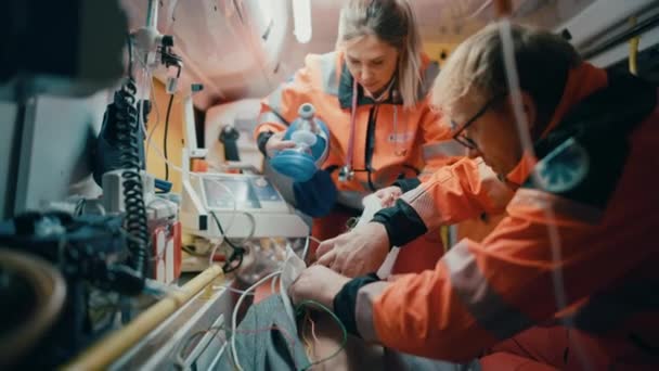 Ratownicy medyczni zapewniający pomoc medyczną pacjentowi w ambulansie — Wideo stockowe