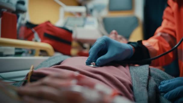 A mentősök sztetoszkóppal kezelik a beteget a mentőben — Stock videók