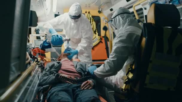 Paramédicos em fatos de macacão Hazmat Suits Fornecendo Ajuda Médica ao Paciente em Ambula — Vídeo de Stock