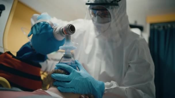 Ensihoitajat haalareissa Hazmat-puvut, jotka tarjoavat lääketieteellistä apua potilaalle Ambulassa — kuvapankkivideo