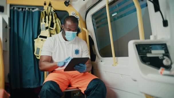 Záchranář v masce obličeje na ambulanci s tabletou — Stock video