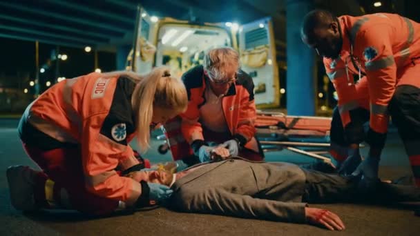 Los paramédicos brindan ayuda médica a un joven acostado en una calle — Vídeos de Stock