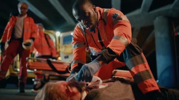 Les ambulanciers fournissent une aide médicale au jeune homme allongé sur une rue — Video