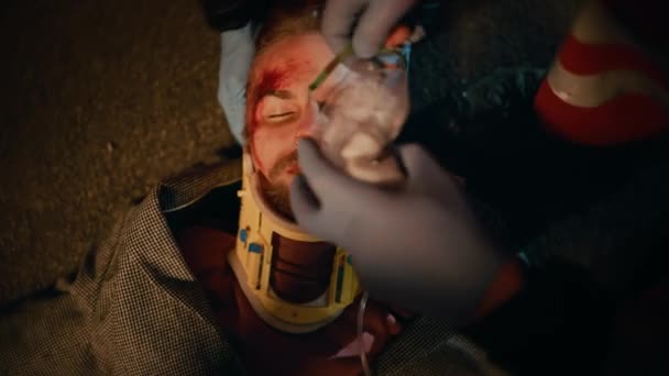 Paramedicinere giver medicinsk hjælp til unge mand liggende på en gade – Stock-video