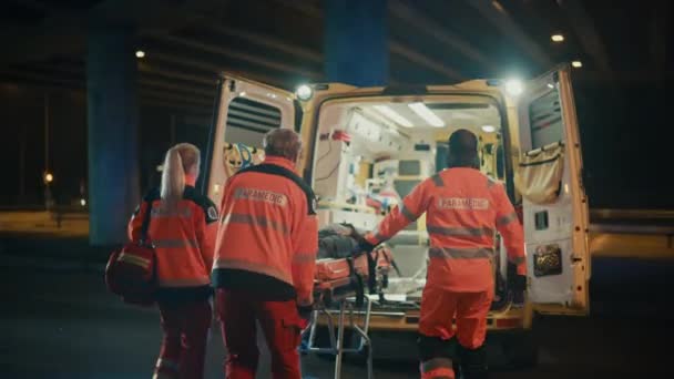 Paramédicos trayendo al paciente dentro de la ambulancia en la camilla — Vídeo de stock