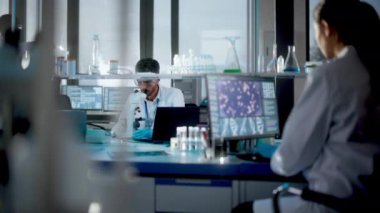 Bilgisayar ve Mikroskop üzerinde çalışan Tıbbi Araştırma Laboratuvarı Bilim Adamları