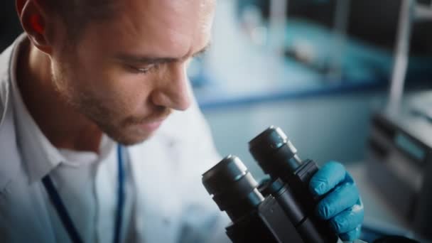 Cercetător de laborator în domeniul cercetării medicale care se uită la microscop — Videoclip de stoc