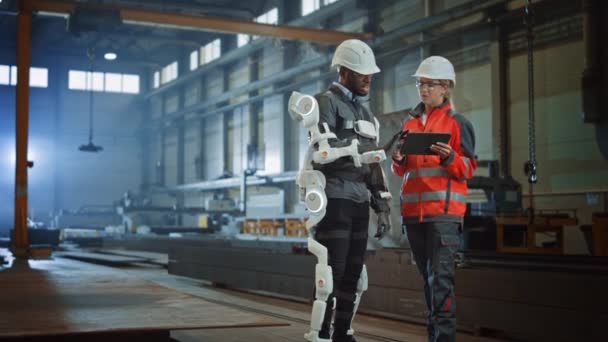 Industrial Factory Worker Bär Exoskelett Samtal med ingenjör på Steel Factory — Stockvideo