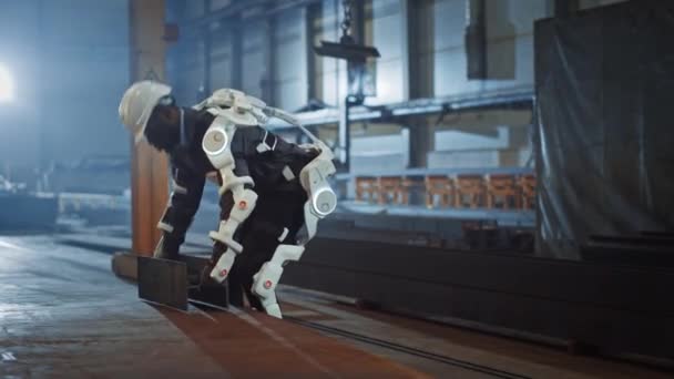O trabalhador industrial da fábrica que usa o exoesqueleto levanta a estrutura de aço pesada — Vídeo de Stock