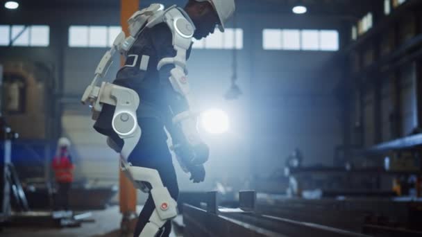 Przemysłowy pracownik fabryki noszący Exoskeleton Lifts Heavy Steel Structure — Wideo stockowe