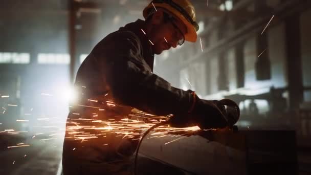 Pracovník pracuje s úhlovou bruskou v průmyslové ocelárně — Stock video