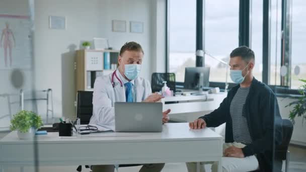 Medische dokter praat met patiënt dragen van gezichtsmaskers — Stockvideo