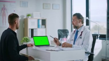 Tıbbi Doktor, Laptop 'ta Hasta ile Konuşuyor ve Yeşil Ekran Modeli Kullanıyor