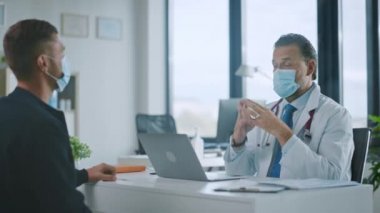 Doktor, yüz maskesi takan hastayla konuşuyor.