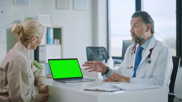 Médecin parle au patient et à l'aide de l'écran vert Mock Up sur ordinateur portable — Video