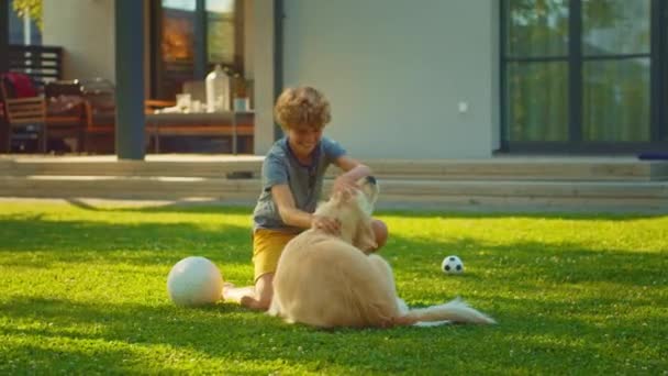 Jongen speelt met Golden Retriever hond in de achtertuin — Stockvideo