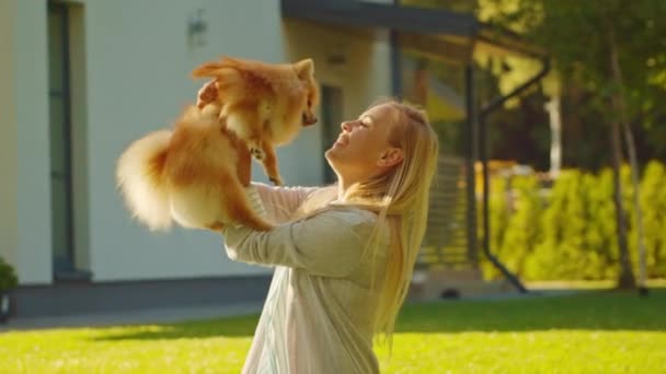 Kobieta bawi się z Cute Pomeranian Dog w podwórku — Wideo stockowe
