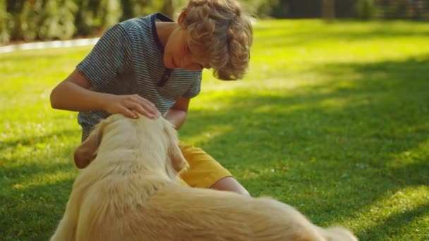 Jongen speelt met Golden Retriever hond in de achtertuin — Stockvideo