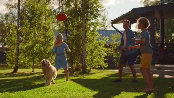 Rodzina gra z Golden Retriever Dog na podwórku — Wideo stockowe